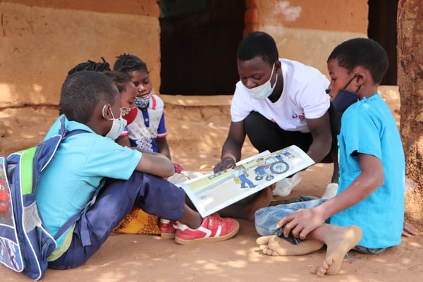 Young male teacher showing book to students in Mozambiue